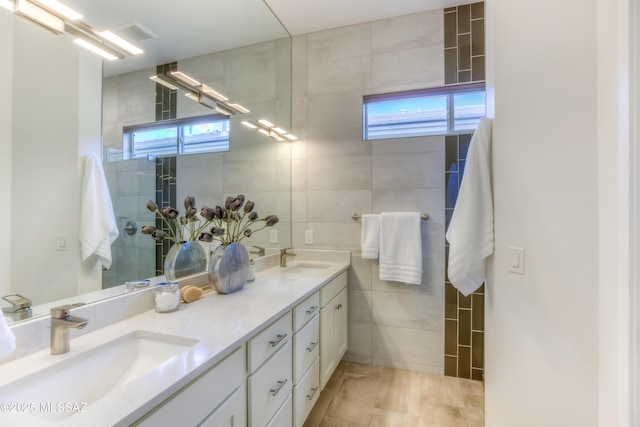 bathroom featuring tile walls, plenty of natural light, double vanity, and a sink