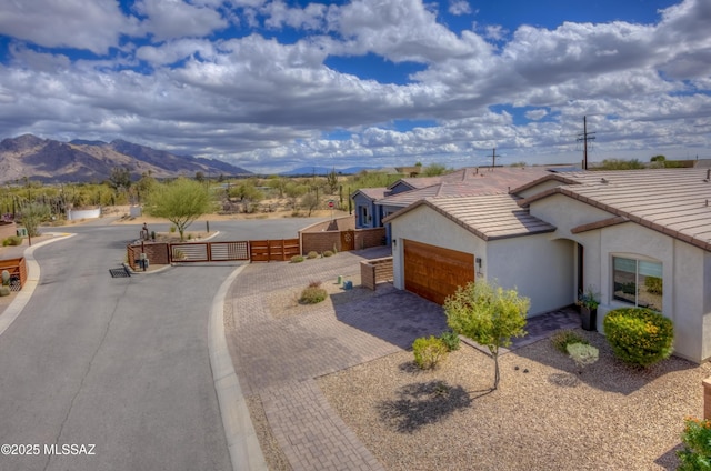 view of front of property with fence, an attached garage, a tiled roof, decorative driveway, and a mountain view