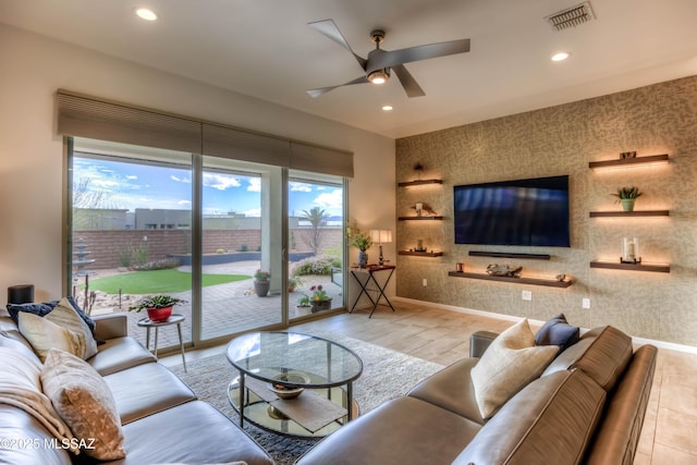 living room with visible vents, wood finished floors, ceiling fan, and an accent wall