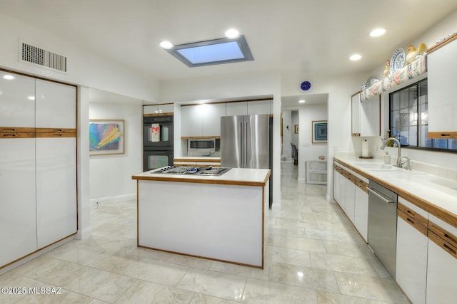 kitchen featuring a center island, light countertops, visible vents, appliances with stainless steel finishes, and white cabinets