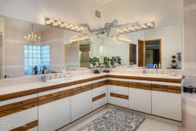 full bath with a chandelier, double vanity, a sink, and tile patterned floors