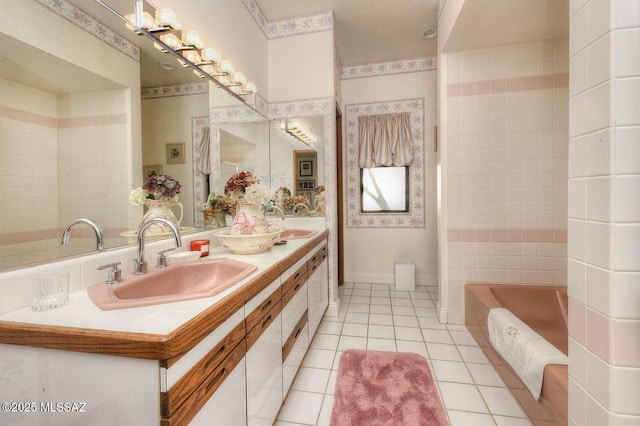 bathroom featuring a washtub, double vanity, a sink, tile patterned flooring, and baseboards