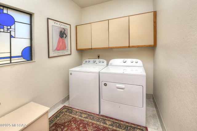 laundry room featuring cabinet space, baseboards, a textured wall, and independent washer and dryer