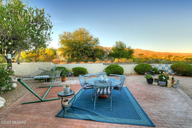 view of patio with outdoor dining space, a mountain view, and fence