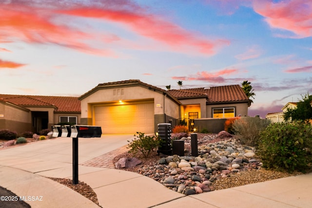 mediterranean / spanish house featuring driveway, a tiled roof, a garage, and stucco siding