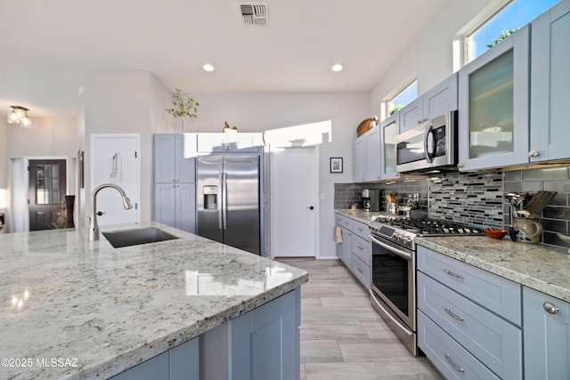 kitchen with visible vents, decorative backsplash, light stone counters, appliances with stainless steel finishes, and a sink