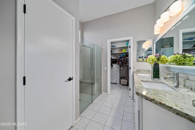 bathroom featuring double vanity, a spacious closet, a stall shower, a sink, and tile patterned floors