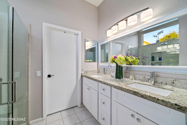 bathroom with double vanity, tile patterned flooring, a tile shower, and a sink