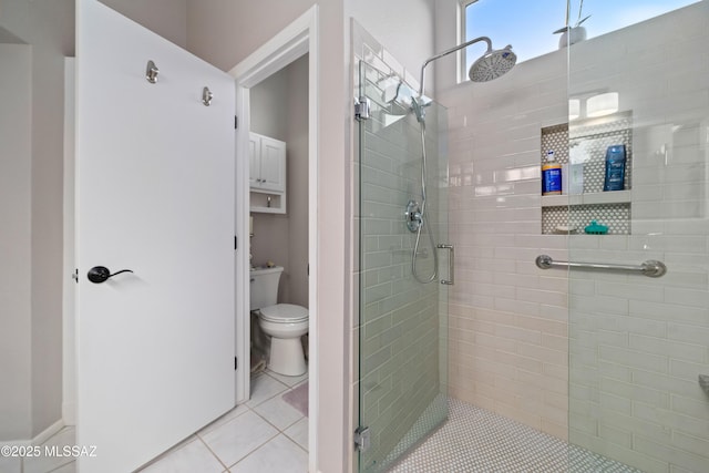 bathroom featuring toilet, a stall shower, and tile patterned flooring