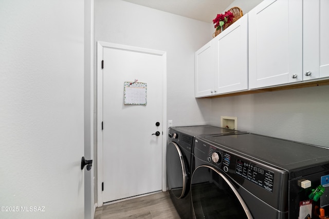 washroom featuring cabinet space, light wood-style floors, and washing machine and clothes dryer