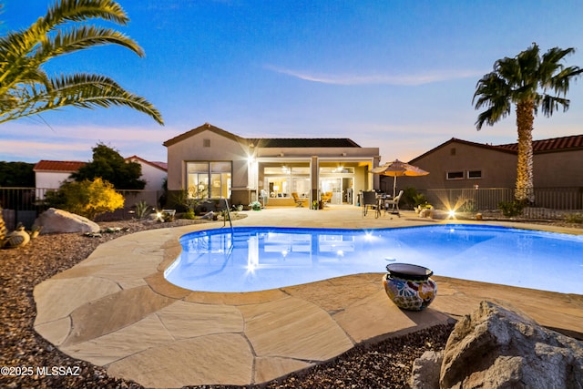 pool at dusk featuring a patio, fence, and a fenced in pool