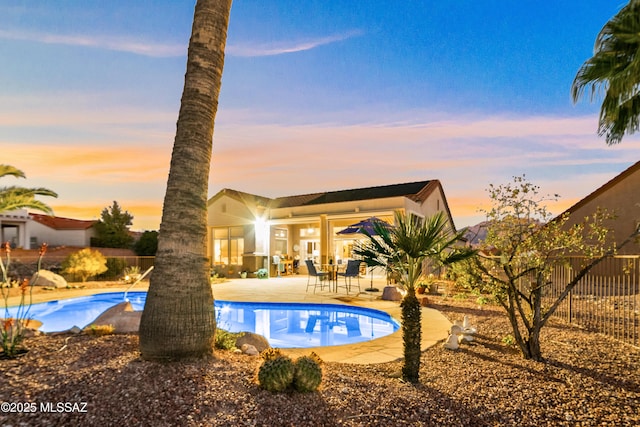 pool at dusk featuring a patio area, fence, and a fenced in pool