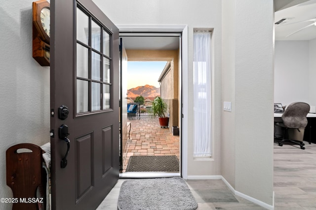 foyer featuring a textured wall, wood finished floors, visible vents, and baseboards