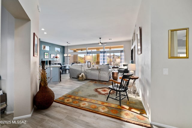 living area with light wood finished floors, ceiling fan, baseboards, and recessed lighting