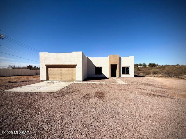 pueblo-style house featuring stucco siding, driveway, and a garage