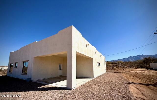 back of house featuring a patio area, a mountain view, and stucco siding