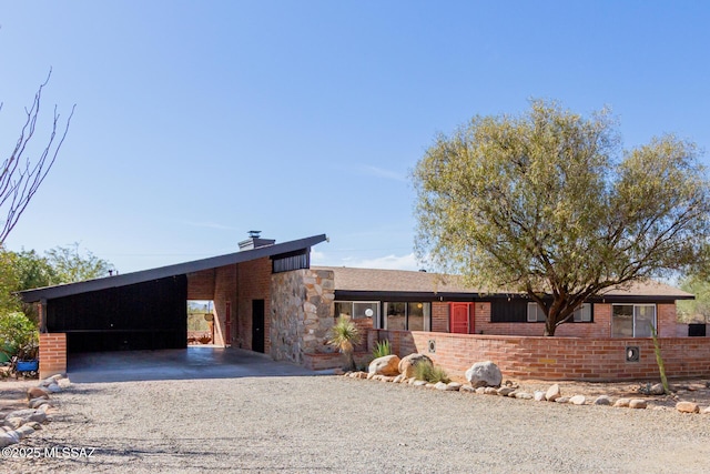 view of front of property with a carport, stone siding, brick siding, and driveway