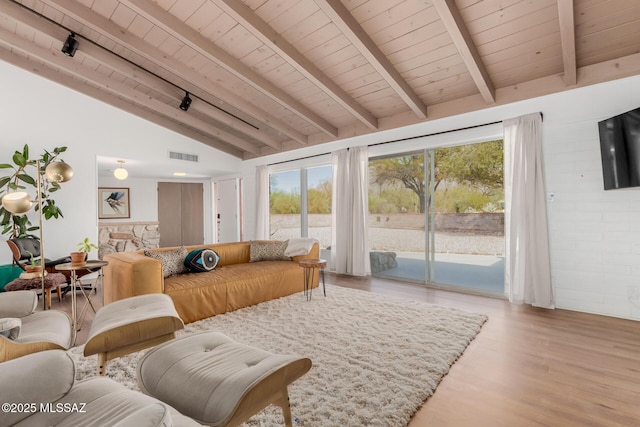 living room featuring lofted ceiling with beams, light wood finished floors, visible vents, and a wealth of natural light