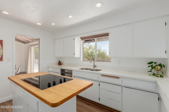 kitchen featuring white cabinets, a kitchen island, a sink, butcher block countertops, and black electric cooktop