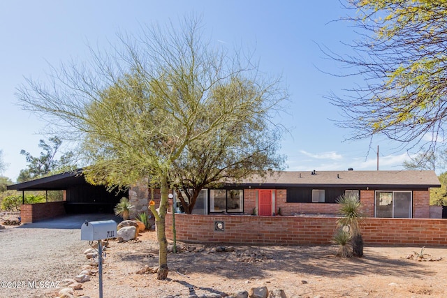 ranch-style house with an attached carport, brick siding, and driveway