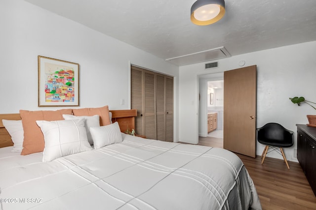 bedroom with attic access, a closet, visible vents, and wood finished floors