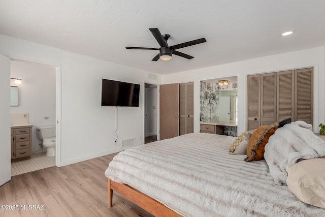 bedroom featuring multiple closets, connected bathroom, visible vents, and light wood-style floors