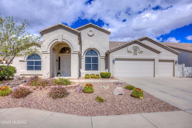 mediterranean / spanish home featuring stucco siding, a tiled roof, driveway, and a garage