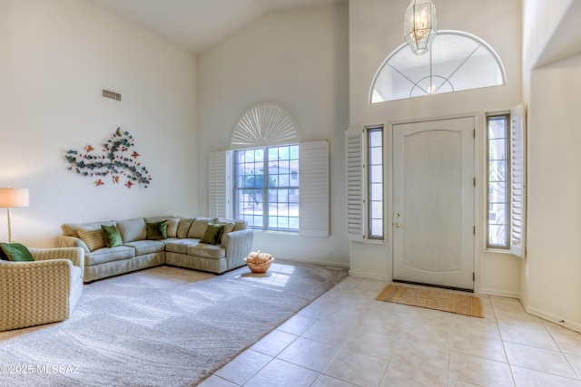 carpeted entrance foyer with a wealth of natural light, visible vents, high vaulted ceiling, and tile patterned flooring