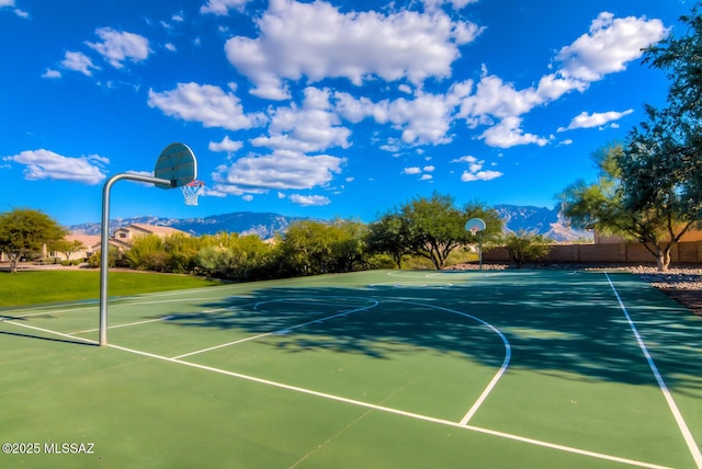 view of basketball court with a mountain view, community basketball court, and fence