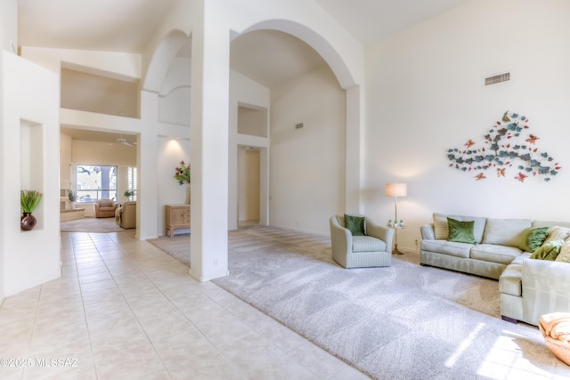 living room with visible vents, light carpet, light tile patterned floors, arched walkways, and high vaulted ceiling