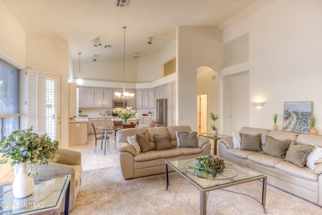 living area with light tile patterned floors, a notable chandelier, light carpet, and high vaulted ceiling