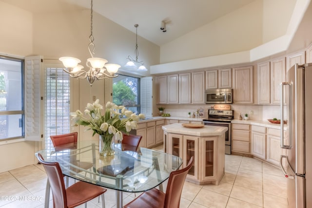 kitchen with high vaulted ceiling, light brown cabinetry, stainless steel appliances, a notable chandelier, and a center island