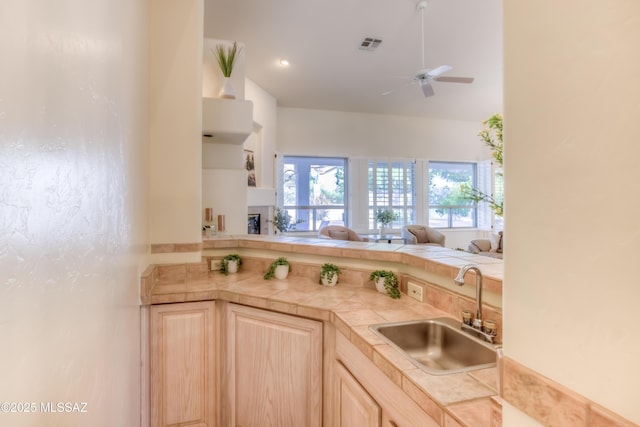 kitchen featuring visible vents, light brown cabinets, open floor plan, a ceiling fan, and a sink