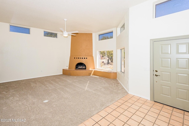 entryway with light tile patterned floors, baseboards, a fireplace, light colored carpet, and ceiling fan