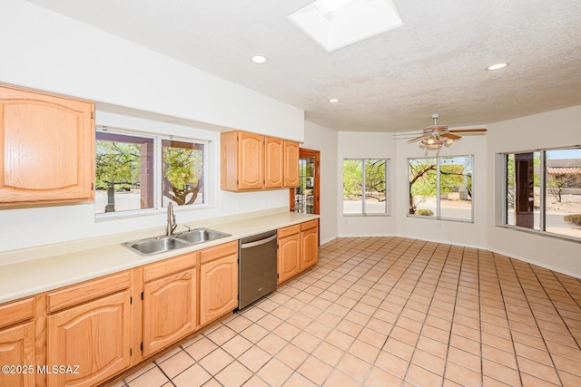 kitchen featuring a sink, a skylight, dishwasher, light countertops, and recessed lighting