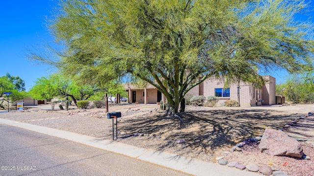 view of property hidden behind natural elements with brick siding