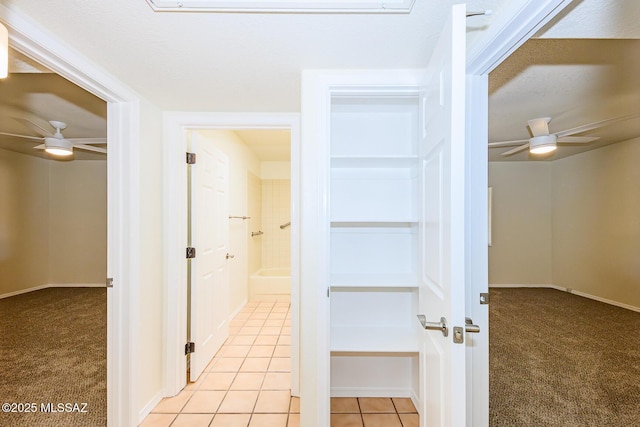 corridor featuring light colored carpet, light tile patterned floors, and baseboards