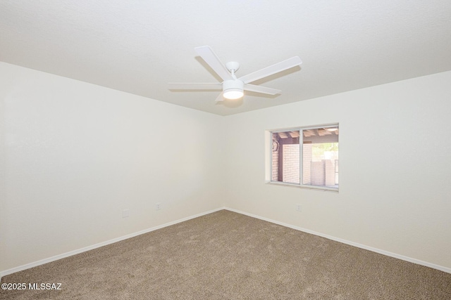 carpeted spare room featuring ceiling fan and baseboards