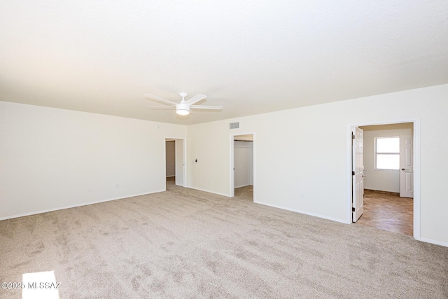 unfurnished room with visible vents, a ceiling fan, baseboards, and light carpet