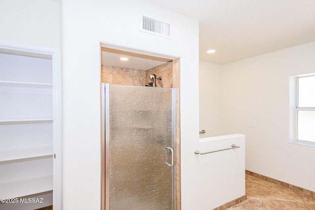 bathroom with a spacious closet, a shower stall, visible vents, and tile patterned flooring