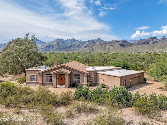 view of front of property featuring a chimney, stucco siding, a mountain view, a garage, and driveway