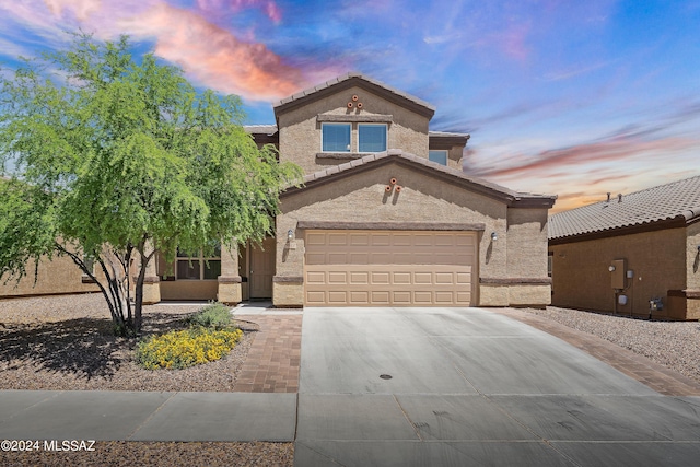 mediterranean / spanish-style house featuring a garage, driveway, a tiled roof, and stucco siding