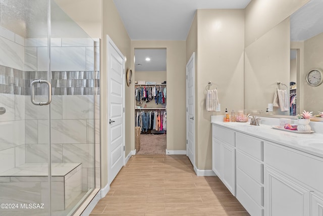 full bath with wood finished floors, vanity, baseboards, a spacious closet, and a shower stall