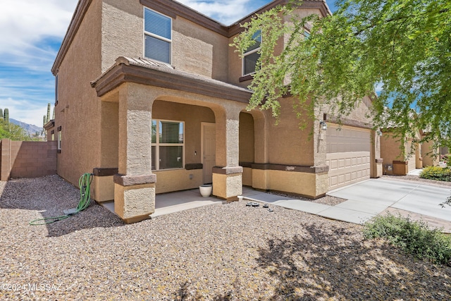 view of front of property with fence, driveway, and stucco siding