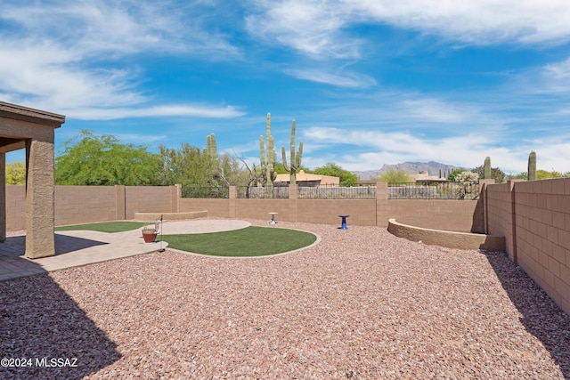 view of yard featuring a patio area, a mountain view, and a fenced backyard