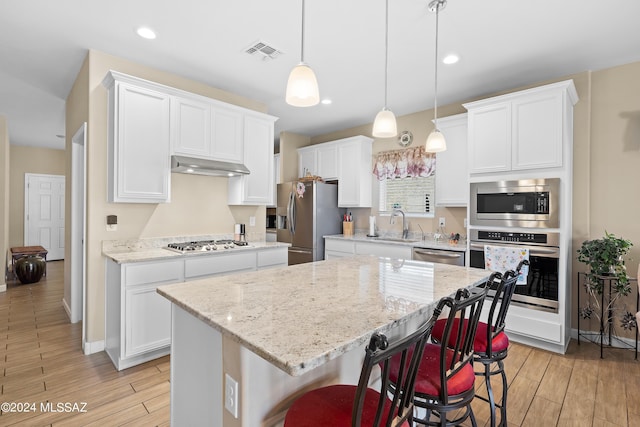 kitchen featuring a center island, stainless steel appliances, visible vents, white cabinets, and under cabinet range hood