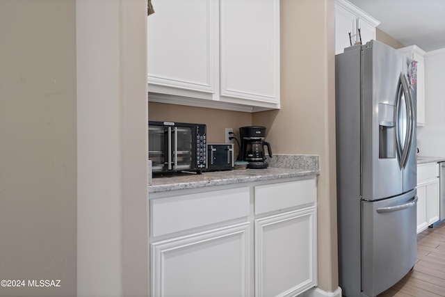 kitchen with light wood-style floors, light stone countertops, white cabinetry, and stainless steel fridge with ice dispenser