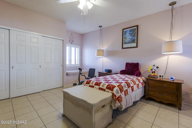 bedroom featuring light tile patterned floors, a textured ceiling, a ceiling fan, and a closet