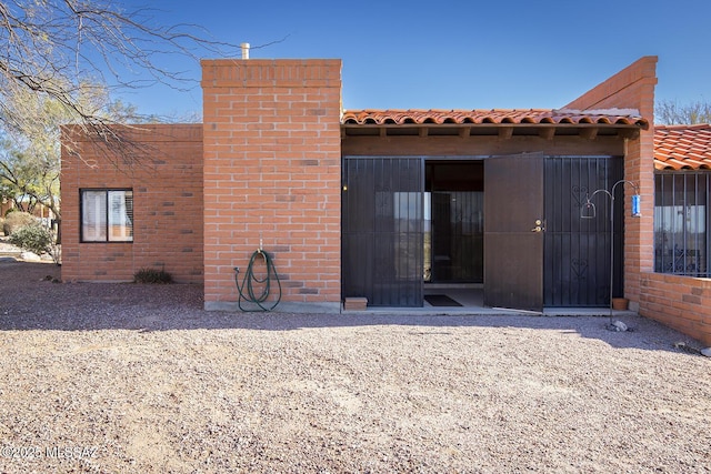 back of house with a tiled roof and a chimney