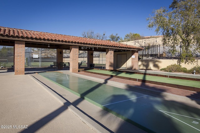 view of property's community featuring shuffleboard and fence